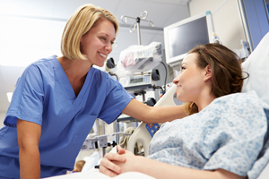Picture of a female Nurse talking with a female patient while patient is in a hospital bed