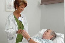 Picture of A Nurse is holding a patient hand while the patient is laying in the hospital bed